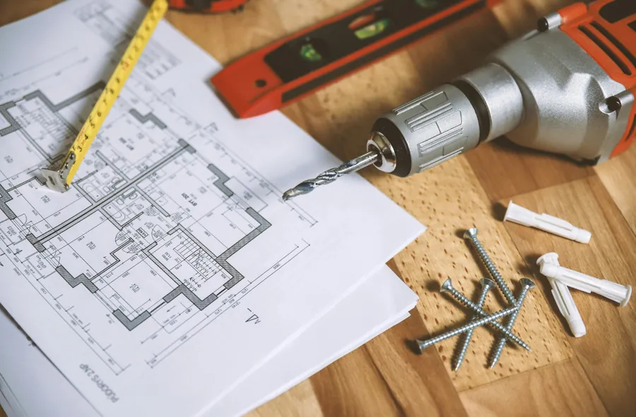 Planos de obra con taladro y herramientas